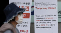 A woman weaning a face mask walks near the notice showing a temporarily closed as a precautions against the coronavirus outside of the National Museum of Korean Contemporary History in Seoul, South Korea, Tuesday, Sept. 1, 2020. South Korea reported more than 200 new cases, mostly from the greater capital area, where officials have restricted dining at restaurants and shut down churches, nightspots, fitness centers and after-school academies to fight a viral resurgence. (AP Photo/Lee Jin-man)