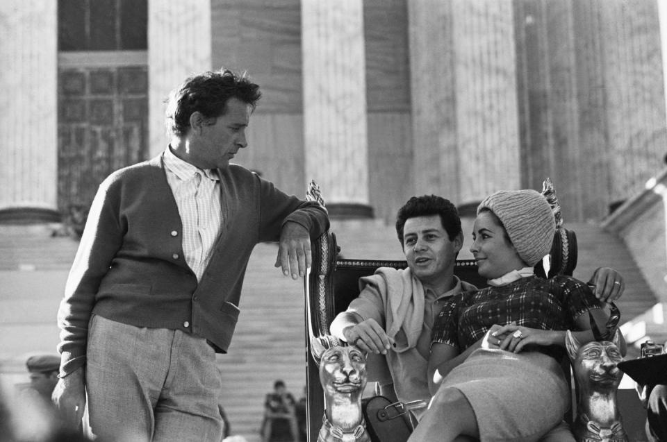 <p>During a visit on the set of <em>Cleopatra </em>in 1961<em>, </em>Elizabeth and Eddie are seen cuddling while he chats up Liz's costar, Richard Burton. However, Elizabeth and Eddie would divorce in 1962 and it would later be revealed that Richard and Elizabeth had an affair throughout filming. </p>