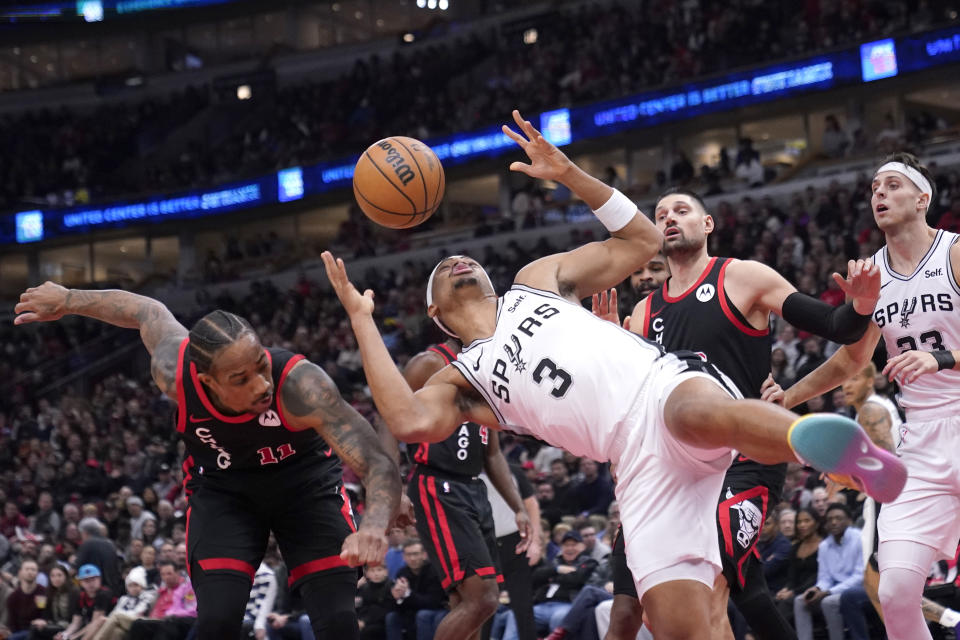 San Antonio Spurs' Keldon Johnson (3) loses control of the ball after his shot was blocked by Chicago Bulls' DeMar DeRozan (11) during the first half of an NBA basketball game Thursday, Dec. 21, 2023, in Chicago. (AP Photo/Charles Rex Arbogast)