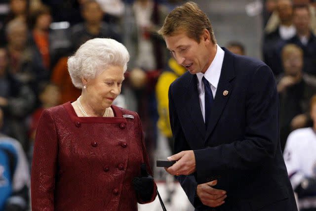 <p>KIM STALLKNECHT/AFP via Getty</p> Queen Elizabeth receives the ceremonial puck presented to her by former Edmonton Oilers and general manager of the men's Olympic hockey team Wayne Gretzky on October 6, 2002, in Vancouver, Canada.