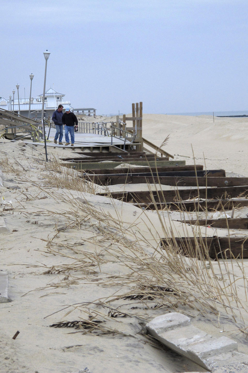 Pedestrians walk up to the edge of what had been the Sea Girt, N.J. boardwalk on Jan. 9, 2013, several months after it was destroyed by Superstorm Sandy. On Feb. 23, 2024, New Jersey selected 18 Jersey Shore towns to split $100 million in funds to repair or rebuild their boardwalks. (AP Photo/Wayne Parry)