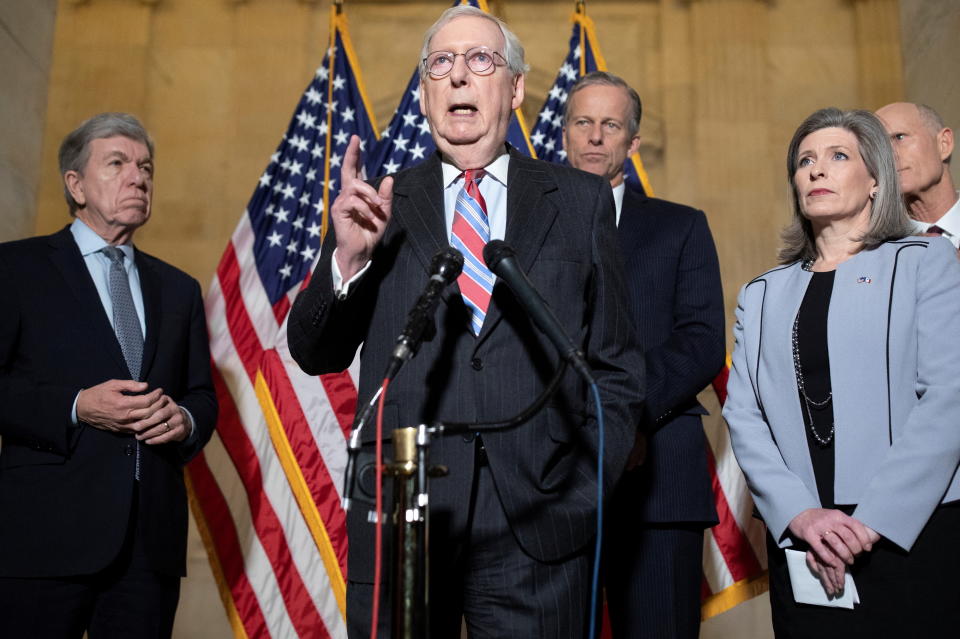 Senate Minority Leader Mitch McConnell, R-Ky., at a microphone surrounded by four people.