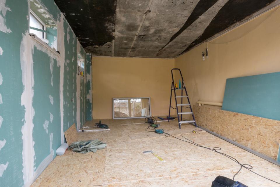 Empty garage under renovation, with drywall taped and mudded on one wall.