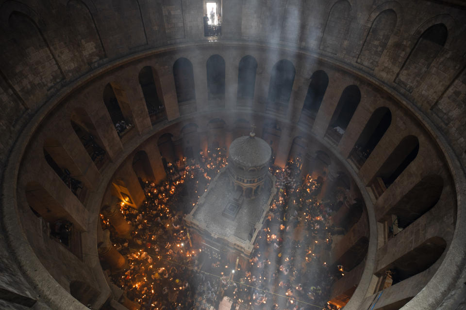 FILE - Christian pilgrims hold candles as they gather during the ceremony of the Holy Fire at Church of the Holy Sepulchre, where many Christians believe Jesus was crucified, buried and rose from the dead, in the Old City of Jerusalem on May 1, 2021. Christians have vowed to defy what they say are new and unfair Israeli restrictions on the "Holy Fire" ceremony to be held Saturday, April 23, 2022 at Christianity's holiest site, raising the possibility of even more religiously-charged unrest in Jerusalem. (AP Photo/Oded Balilty, File)