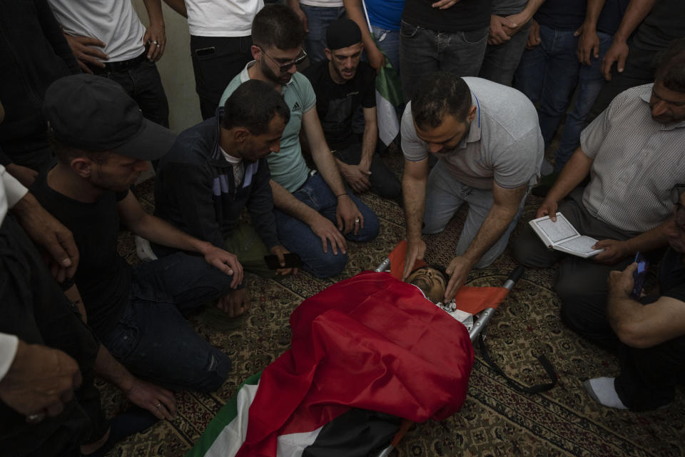 Mourners take the last look at the body of Yahia Edwan, 27 at a mosque during his funeral at the West Bank village of Azzoun, near Qalqiliya, Saturday, April 30, 2022. Israeli troops shot and killed Edwan early Saturday, the Palestinian Health Ministry said. The Israeli army said it had opened fire after a group of suspects threw firebombs toward the soldiers. (AP Photo/Nasser Nasser)
