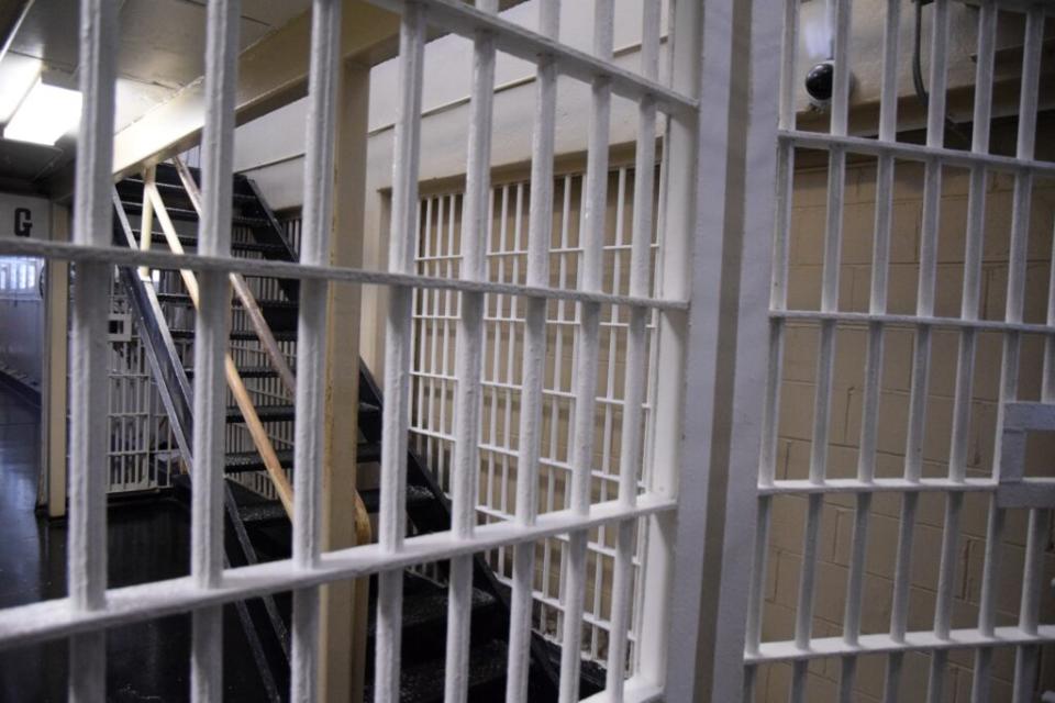 Bars in a prison. A staircase can be seen behind them.