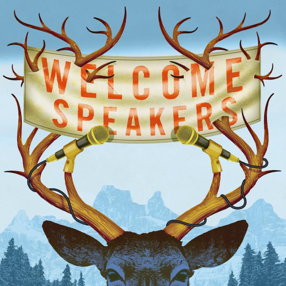 A deer with a "welcome speakers" sign in its antlers
