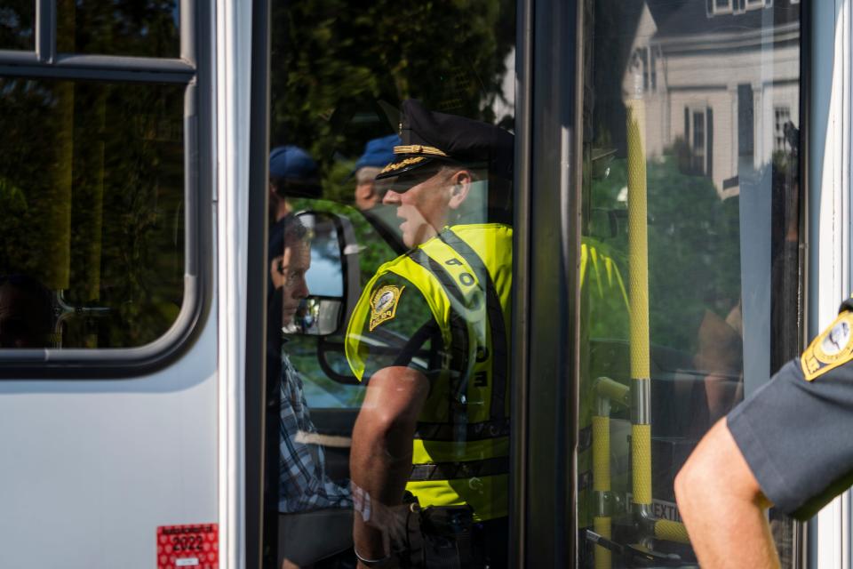 A police officer is seen in reflection next to a bus.