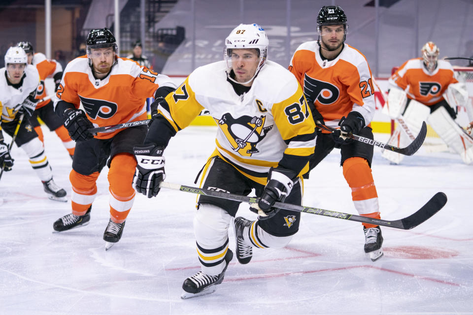 Pittsburgh Penguins' Sidney Crosby, center, heads after the puck after winning the face off against Philadelphia Flyers' Scott Laughton, right, with Michael Raffl, left, following during the third period of an NHL hockey game, Wednesday, Jan. 13, 2021, in Philadelphia. The Flyers won 6-3. (AP Photo/Chris Szagola)