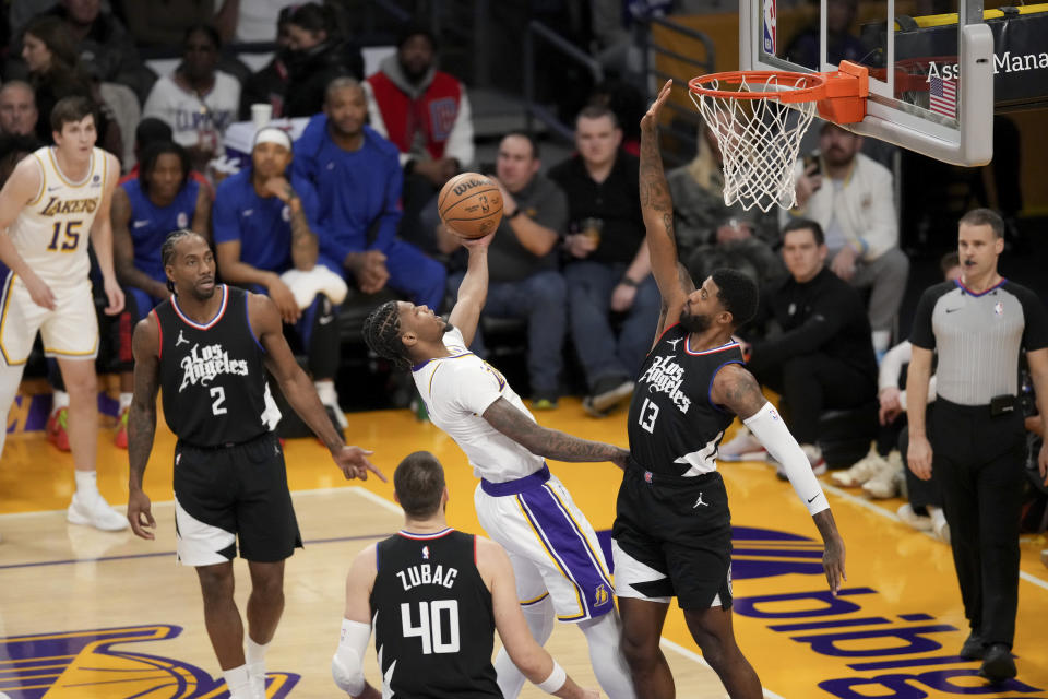 Los Angeles Lakers forward Cam Reddish, center top, drives to the basket against Los Angeles Clippers forward Paul George (13) during the first half of an NBA basketball game in Los Angeles, Sunday, Jan. 7, 2024. (AP Photo/Eric Thayer)