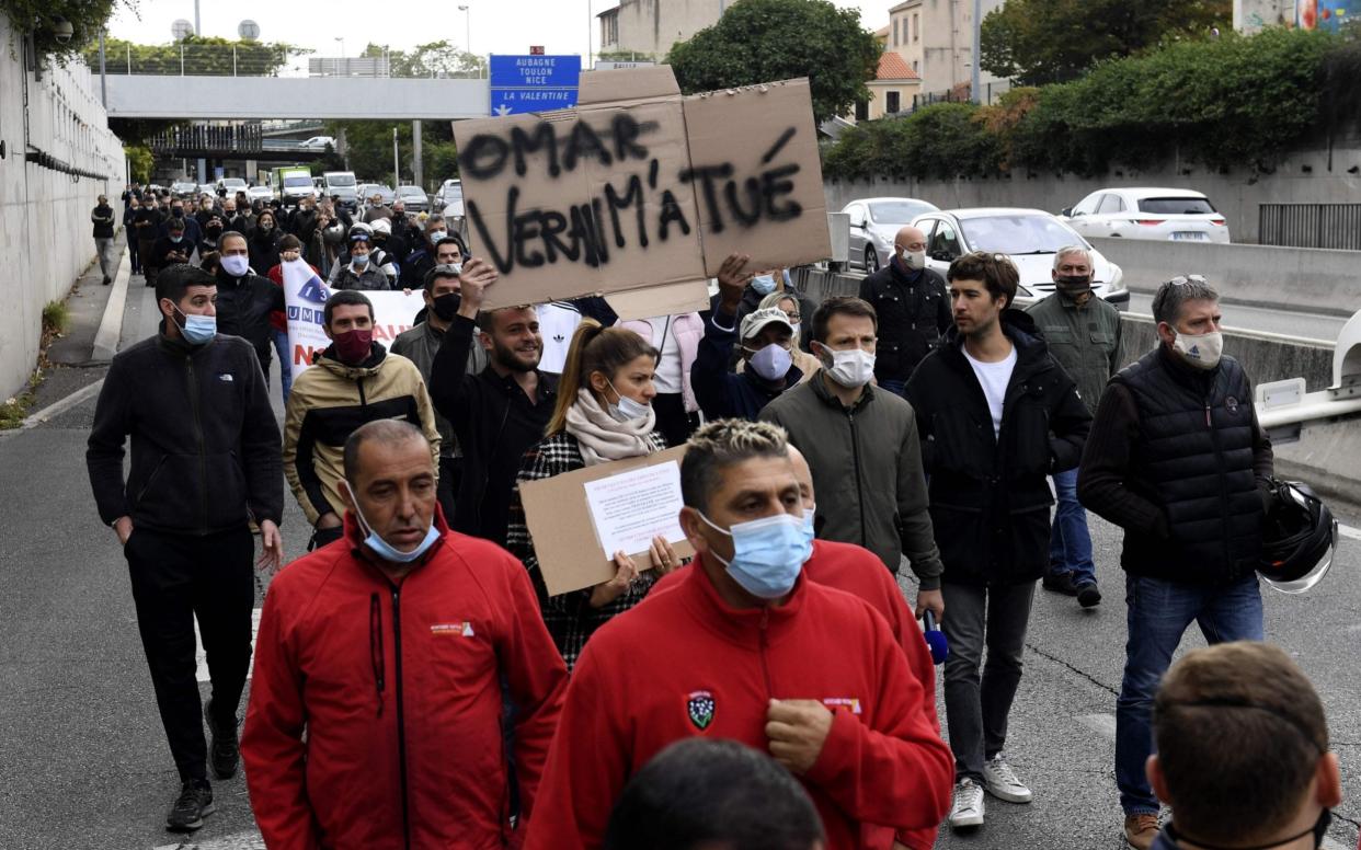 A protester holds a placard reading "Veran (Health Minister) killed me" during a demonstration by bars and restaurants owners in Marseille - NICOLAS TUCAT /AFP