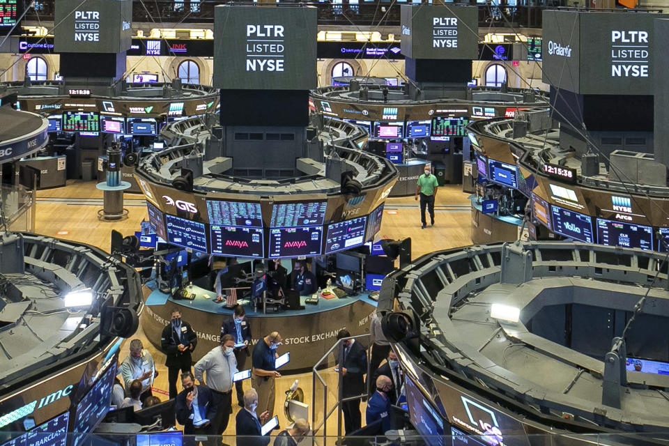 In this photo provided by the New York Stock Exchange, traders, foreground center, gather at a post on the NYSE trading floor during the direct listing of Palantir Technologies, Wednesday, Sept. 30, 2020. Shares of data-mining company Palantir jumped 47% to $10.67 on their first day of trading. The company was born 17 years ago with the help of CIA seed money. Palantir isn't selling new shares to raise money. Instead, it's listing existing shares for public trading. (NYSE Photo/Courtney Crow via AP)