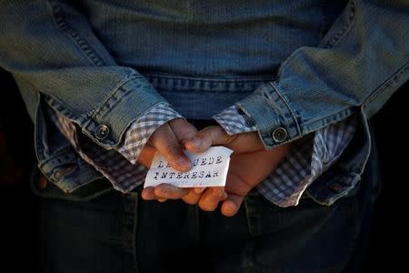 FILE PHOTO: A man holds a paper with a job offer which reads, " You might want to", as he waits in line to enter a government job centre in Malaga, southern Spain March 2, 2011. REUTERS/Jon Nazca/File Photo