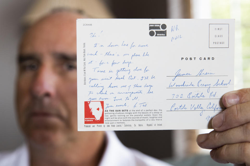 FILE - In this Friday, July 26, 2019 file photo, James Grein, 61, at his house in Sterling, Va., holds a Florida postcard sent to him when he was 15 years old by now-defrocked Cardinal Theodore McCarrick. Grein says the now-defrocked Cardinal Theodore McCarrick's exalted place in the family over three generations created pressure on him to visit with McCarrick during weekends away from boarding school and visits when he would be molested. "If I didn't go to see Theodore I was always going to be asked by my brothers and sisters or my dad, 'Why didn't you go see him?'" (AP Photo/Manuel Balce Ceneta)