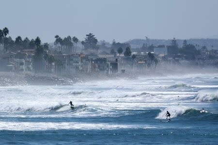 Surfers cool off in the waves during a Southern California heat wave in Oceanside, California, U.S., October 24, 2017. REUTERS/Mike Blake