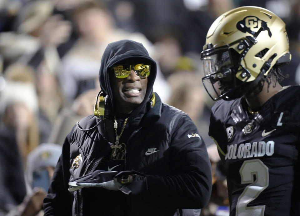 Colorado coach Deion Sanders, left, talks to quarterback Shedeur Sanders, his son, during the first half of the team's NCAA college football game against Stanford on Friday, Oct. 13, 2023, in Boulder, Colo. (AP Photo/David Zalubowski)