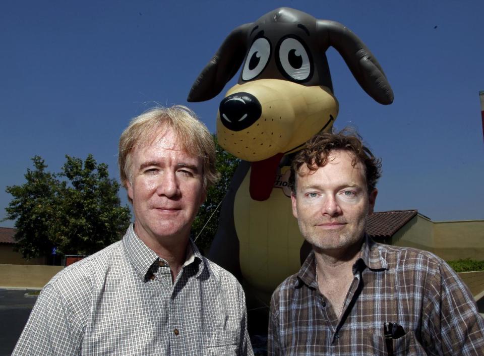 In this Thursday, June 14, 2012 photo, Brandon Camp, right, writer, producer and director of the upcoming feature film remake of "Benji," and animal trainer Mark Forbes, pose in front of a large inflated figure of a dog at the Best Friends Animal Society shelter in the Mission Hills area of Los Angeles. Camp, whose father created "Benji" nearly 40 years ago, and veteran movie trainer Forbes have set out to find a new Benji in a nationwide search that includes online tools and sites that weren't around when the first four Benjis were discovered. (AP Photo/Reed Saxon)