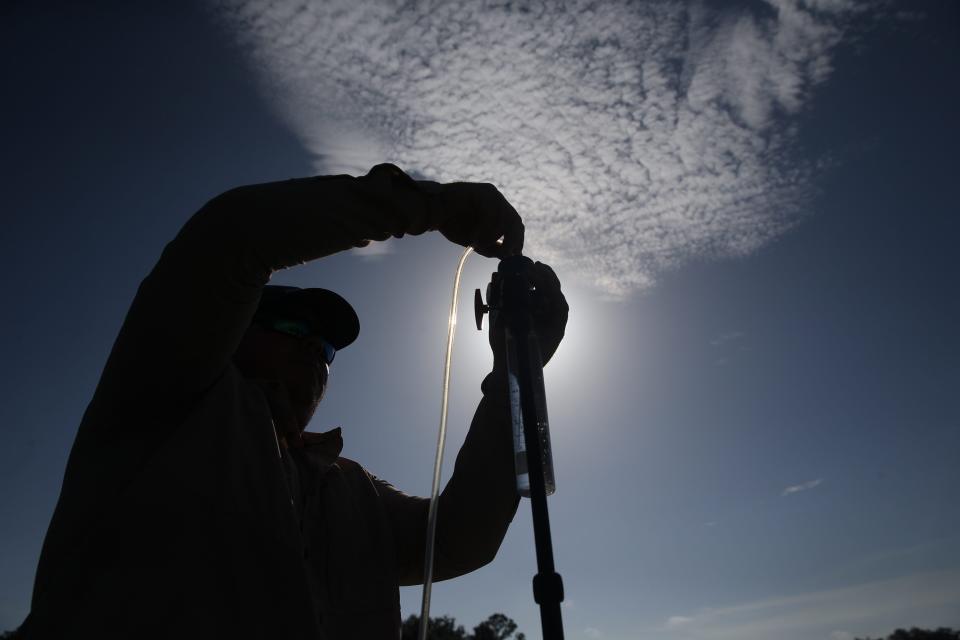 Codty Pierce, the Calusa Waterkeeper sets up an aerosol detection for algae monitoring unit along the Caloosahatchee River in Alva on Wednesday, July, 19, 2023. The unit will be deployed for 24 hours and will collect air samples which includes cyanotoxins. Pockets of the river and its tributaries are seeing blue green algae.