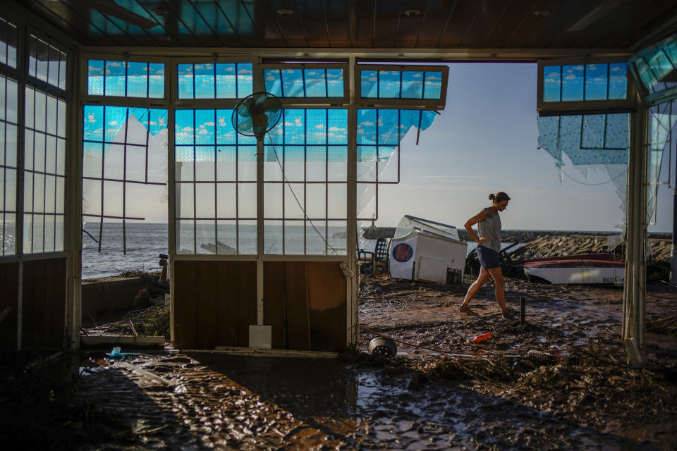 FILE - Carla Bayerri, 45, inspects her restaurant after flooding in the seaside town of Alcanar, in northeastern Spain, Sept. 2, 2021. Damage wrought by Hurricane Ida in the U.S. state of Louisiana and the flash floods that hit Europe last summer have helped make 2021 one of the most expensive years for natural disasters. Reinsurance company Munich Re said Monday, Jan. 10, 2022 that overall economic losses from natural disasters worldwide last year reached $280 billion. (AP Photo/Joan Mateu Parra, file)