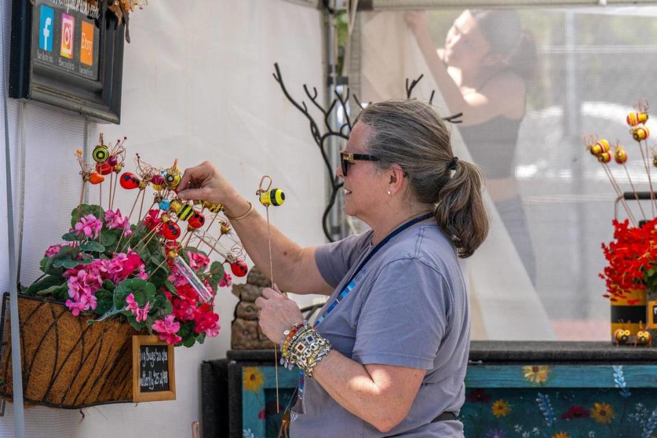 Annette Gordon, from Paola, Kansas, rearranges her garden sculptures while preparing for the Brookside Art Annual on Friday.