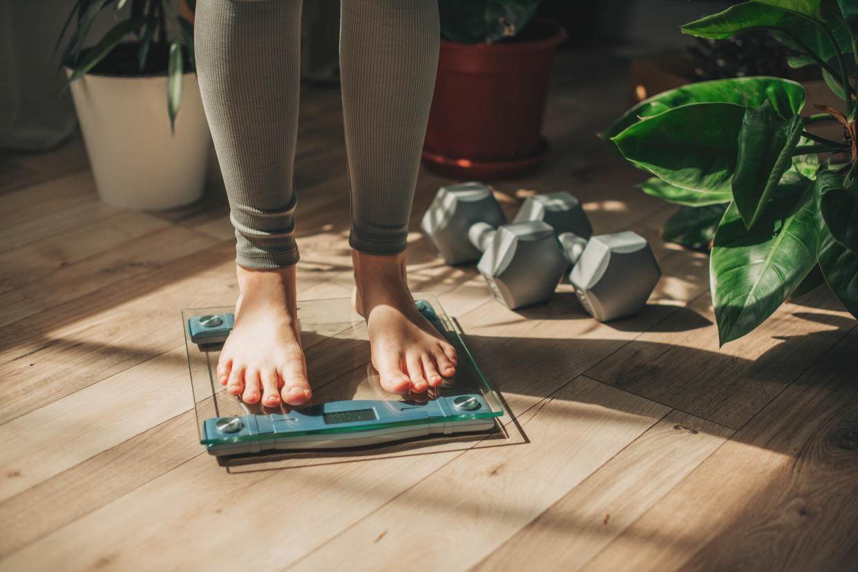 A young woman is weighing herself in a weighing scale