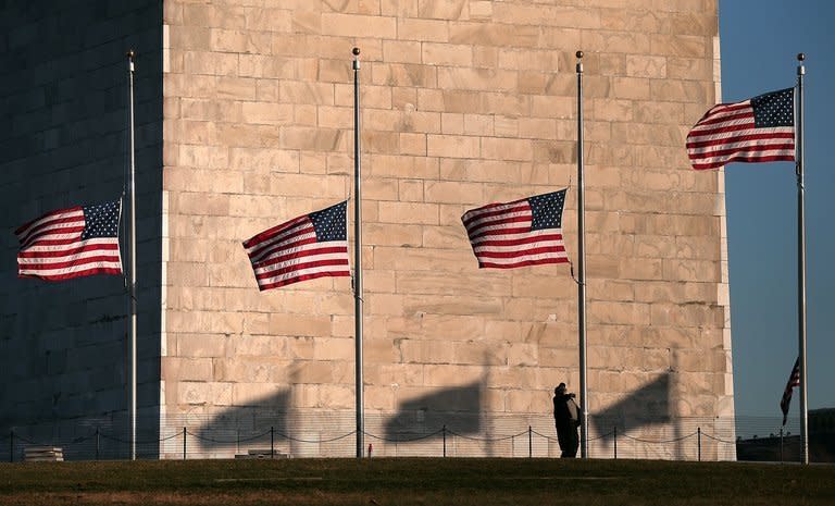 A National Park Service employee lowers flags at the base of the Washington Monument to half staff December 14, 2012 in Washington, DC. The residents of an idyllic Connecticut town were reeling in horror Saturday from the massacre of 20 small children and six adults at a school, in one of the worst mass shootings in US history