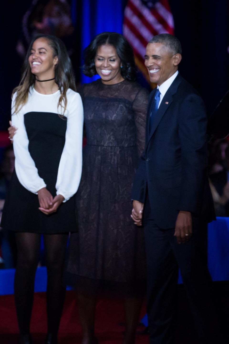 Malia Obama, Michelle Obama, and Barack Obama at an event, smiling