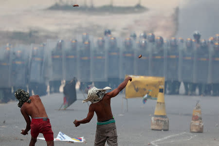 Demonstrators throw stones at a line of Venezuelan national guards at the border in Pacaraima, Brazil February 24, 2019. REUTERS/Ricardo Moraes