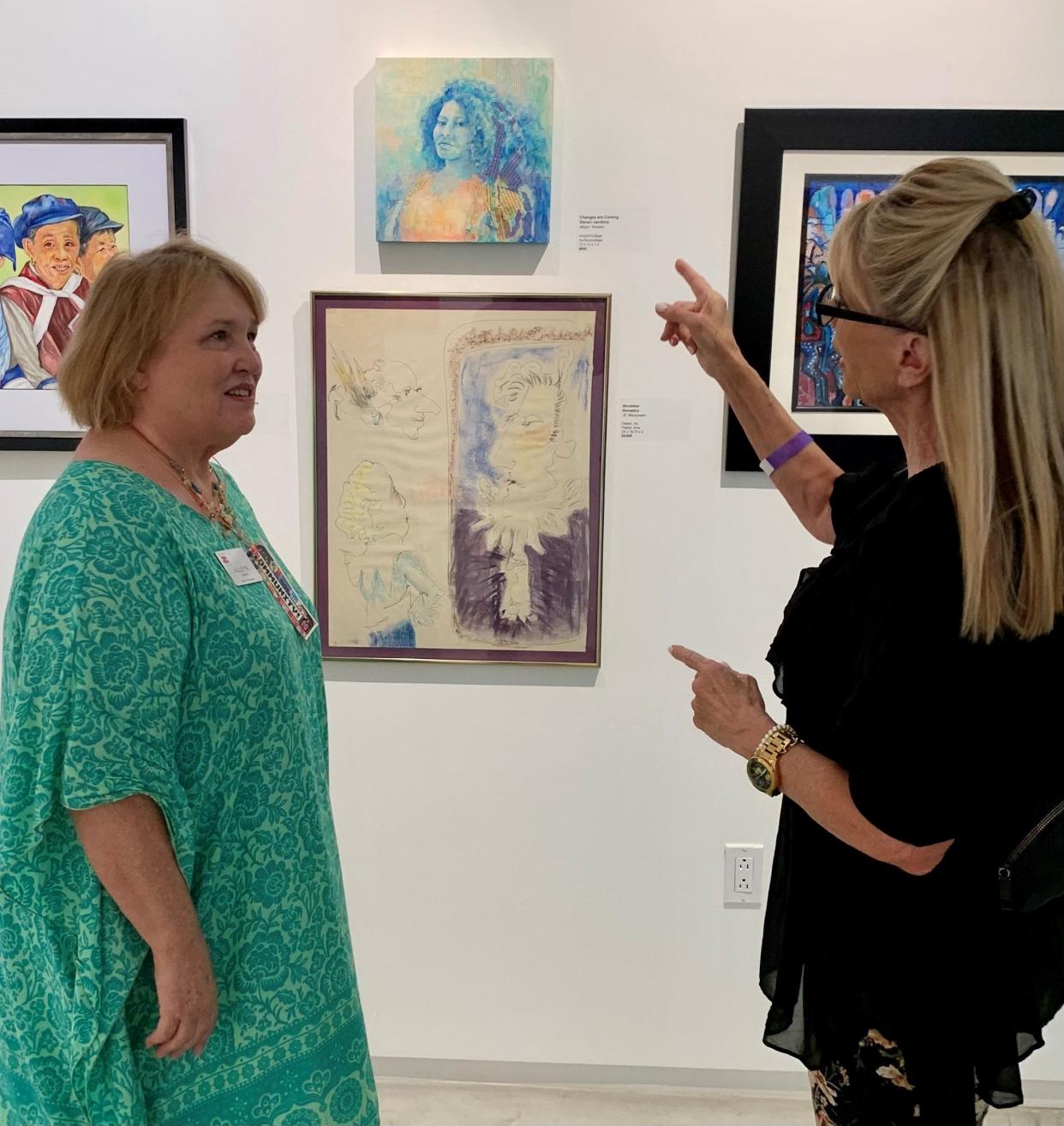 Artist Alleyn Yasskin shows Sandie Newton her art.