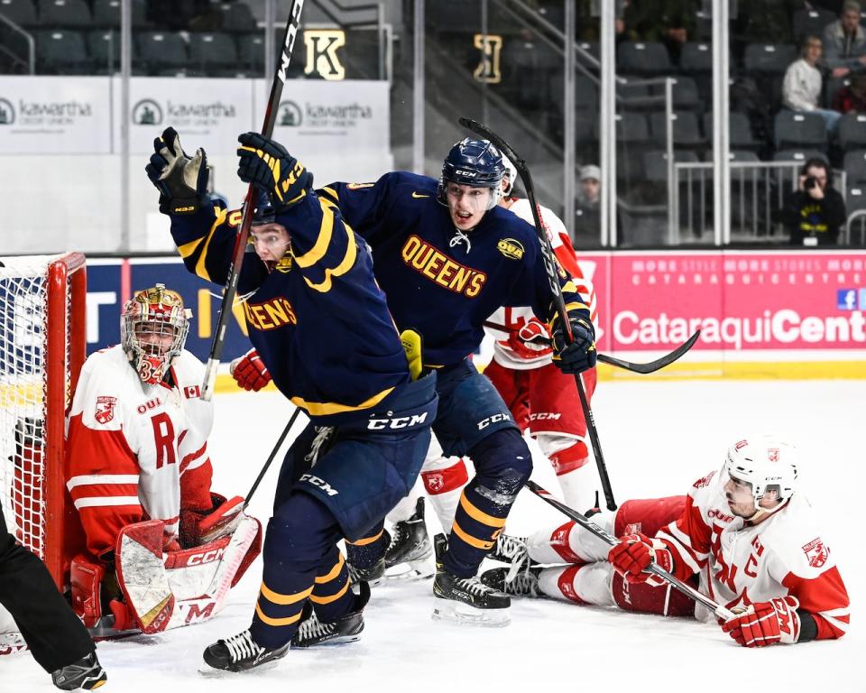 Queen's University men's hockey player Alex Robert, second from left, will be competing in his final Carr-Harris Challenge Cup against Royal Military College on Thursday after scoring the game-winning goal in overtime, pictured above, during last year's rivalry game in February. (James Paddle Grant/Queen's University/File - image credit)