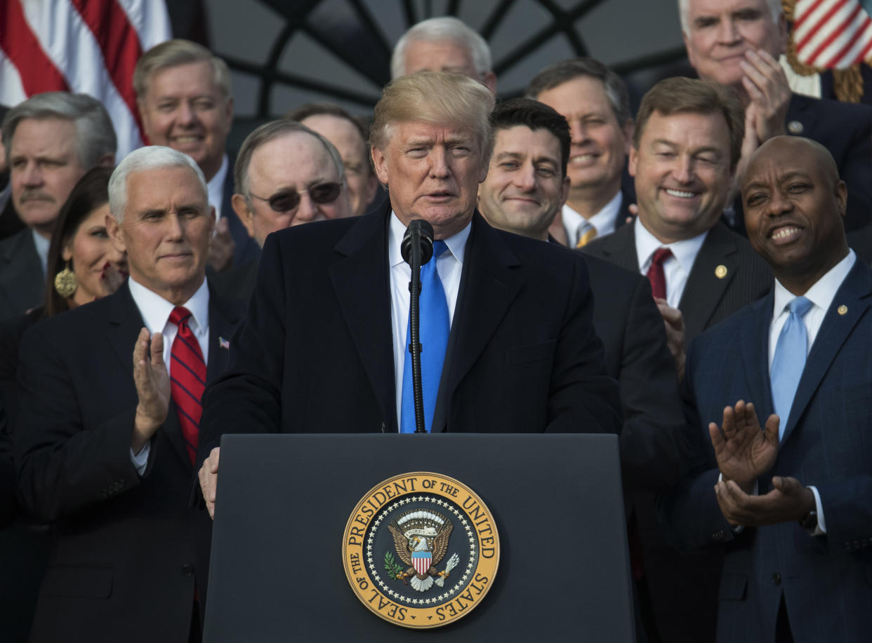 Then-President Donald Trump stands at a podium. Behind him are then-Vice President Mike Pence and a number of Congress members.