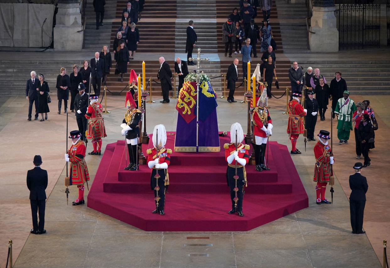 The first members of the public arrive to pay their respects and pass the coffin of Queen Elizabeth II as it Lies in State inside Westminster Hall, at the Palace of Westminster in London on September 14, 2022. - Queen Elizabeth II will lie in state in Westminster Hall inside the Palace of Westminster, from Wednesday until a few hours before her funeral on Monday, with huge queues expected to file past her coffin to pay their respects. (Photo by Yui Mok / POOL / AFP) (Photo by YUI MOK/POOL/AFP via Getty Images)