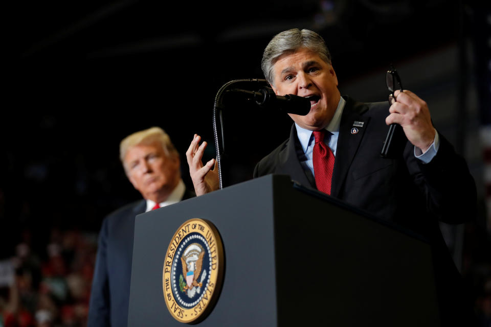 Then President Donald Trump listens as Sean Hannity from Fox News speaks at a campaign rally in Cape Girardeau, Mo., on the eve of the midterm elections in 2018.  