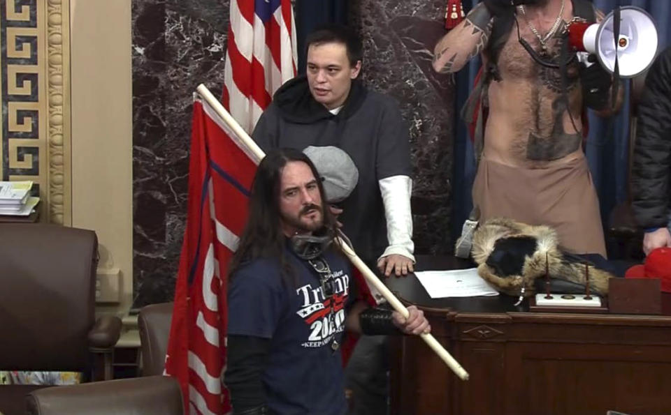 In this image from U.S. Capitol Police video, Paul Allard Hodgkins, 38, of Tampa, Fla., front, stands in the well on the floor of the U.S. Senate on Jan. 6, 2021, at the Capitol in Washington. Hodgkins, who carried a Trump 2020 flag while in the U.S. Senate during the Jan. 6 riot pleaded guilty on Wednesday, June 2, 2021, to a felony charge of obstructing an official proceeding. (U.S. Capitol Police via AP)