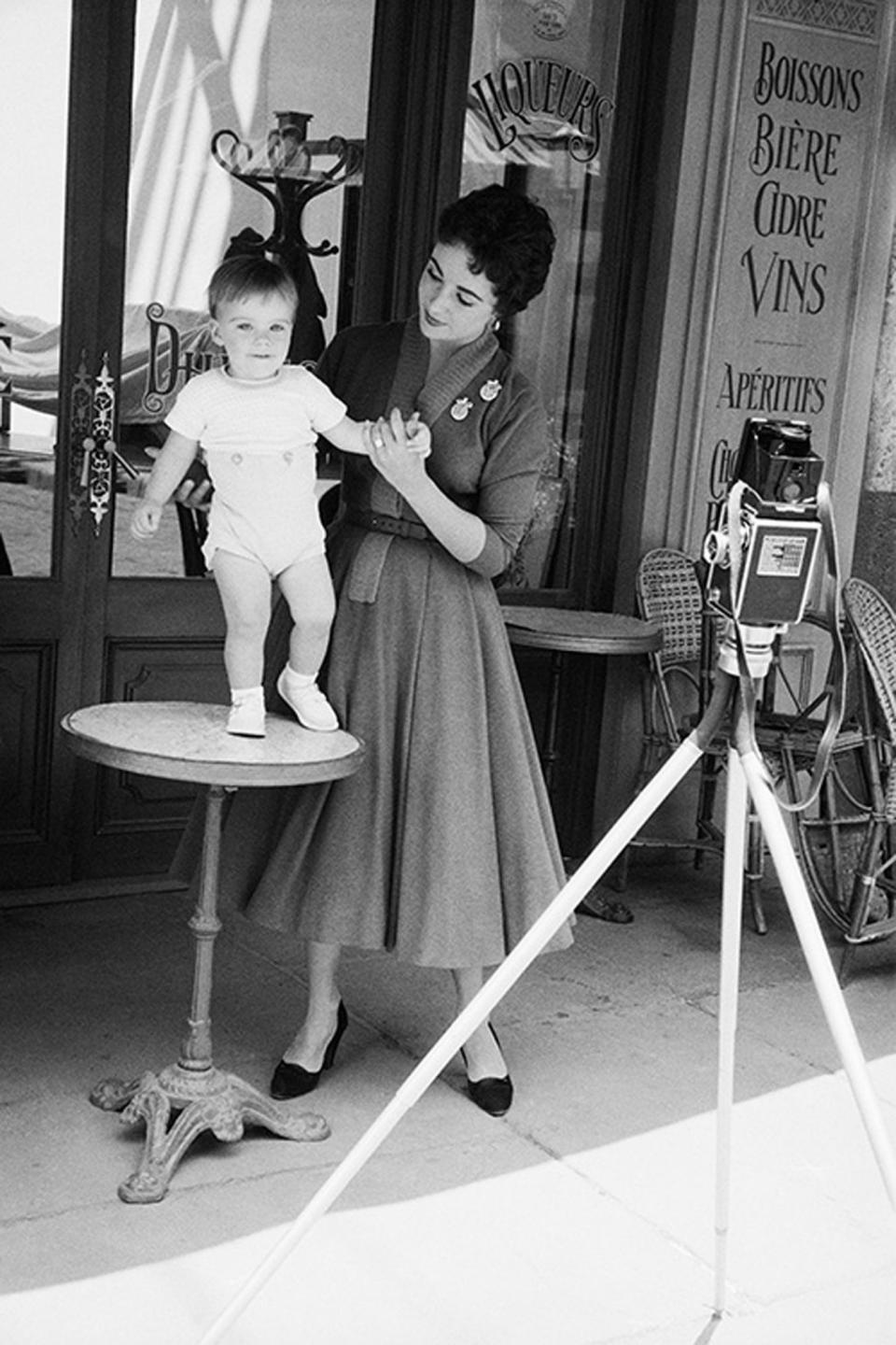 <p>Greene shot the actress with her 16-month-old son, Michael Wilding, Jr., in the MGM back lot. This and other charming images of the mother and son were taken for <em>Look</em> magazine's series of Hollywood mothers. </p> <p>"I sit and watch him all day long when I am home because he's absolutely fascinating. I think he'll grow up to be a wonderful man – something sensational," said Taylor, according to <em>Forever Elizabeth. </em>Michael Wilding, Jr., was the first of two sons that Taylor had with her second husband, also named Michael Wilding. (She had four children in total.) "So far, his favourite pastimes are eating everything, opening the tops of jars and splashing about like mad in a portable pool. He says only two things: 'What's this?' and something that sounds like 'Gee'. Of course, he has never seen his father or me on the screen, and we are doing everything we can to let him have a normal private life of his own."</p>