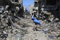 A Palestinian walks through the destruction left by the Israeli offensive on Khan Younis, Gaza Strip, Friday, March 8, 2024. (AP Photo/Hatem Ali)