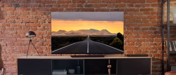 An LG OLED TV in front of a brick wall in a living room