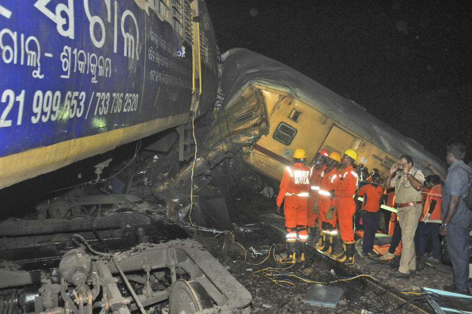 Rescuers and others stand after two passenger trains collided in Vizianagaram district, Andhra Pradesh state, India, Sunday, Oct.29, 2023. The crash happened when an incoming train slammed into a stationary train, leading to derailment of at least three rail cars. (AP Photo)