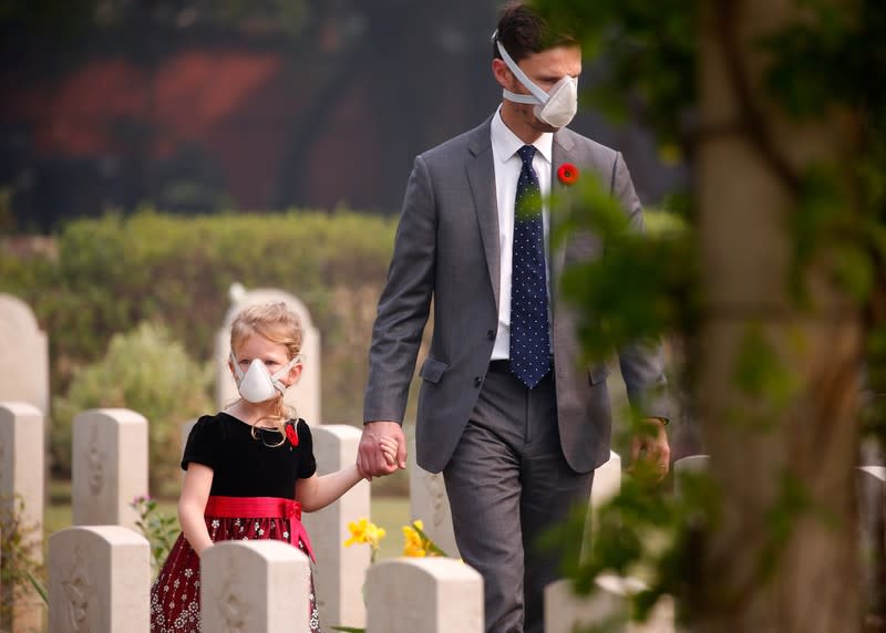 Attendees wearing protective masks walk at Delhi War Cemetery before Britain's Prince Charles' visit to the cemetery in New Delhi