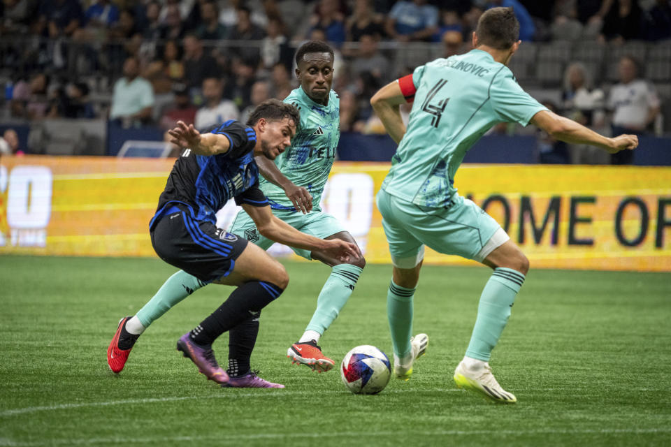 San Jose Earthquakes' Cade Cowell, left, battles Vancouver Whitecaps' Ranko Veselinović (4) and Whitecaps' Richie Laryea, center, during first-half MLS soccer match action in Vancouver, British Columbia, Sunday, Aug. 20, 2023. (Ethan Cairns/The Canadian Press via AP)