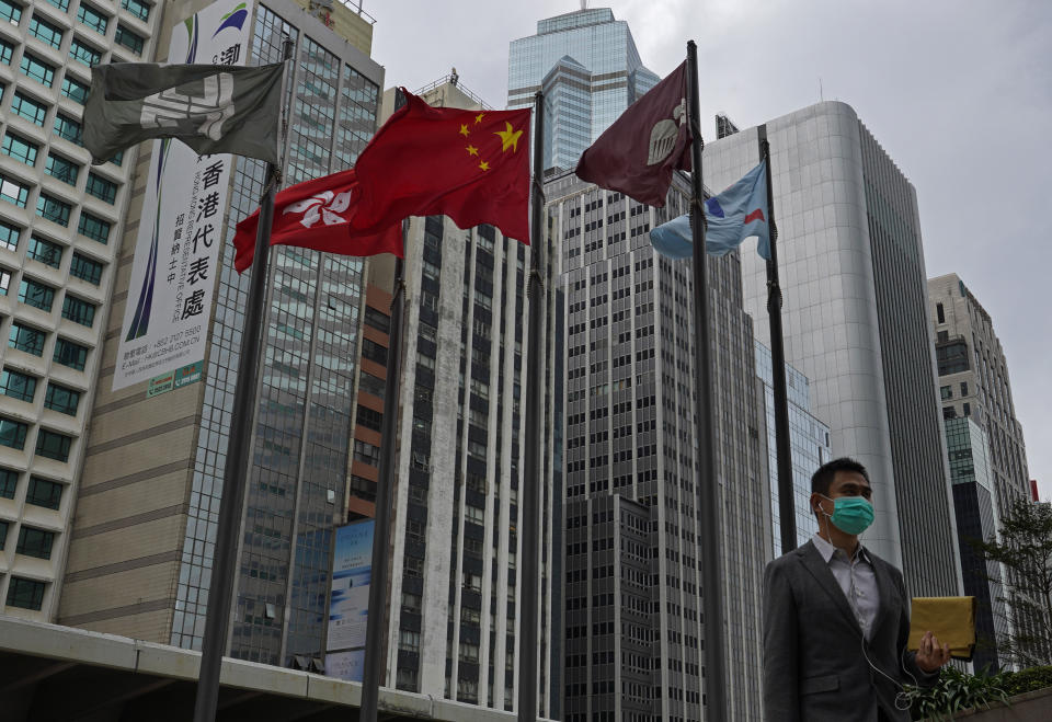 A man wears protective face masks walk past a Chinese national flag on a street in Hong Kong, Monday, Feb, 3, 2020. In Hong Kong, thousands of health care workers were threatening to go on strike Tuesday unless the government agrees to talks before a 6 p.m. Monday deadline. Hong Kong has recorded 14 cases of the virus and has cut flights and train and bus connections to the mainland, but a push is growing for the semi-autonomous Chinese city to close the border completely. (AP Photo/Vincent Yu)