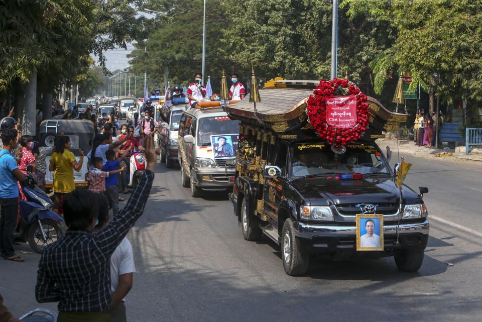 People flash the three-fingered salute as motorcade caring the coffin of Thet Naing Win is driven past in Mandalay, Myanmar, Tuesday, Feb. 23, 2021. Thet Naing Win was shot and killed by Myanmar security forces during an anti-coup protest on Saturday. (AP Photo)