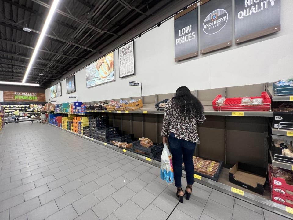 A shopper at the Aldi's in the Town Center mid-morning on Tuesday picking through shelves of bread, which were nearly empty.