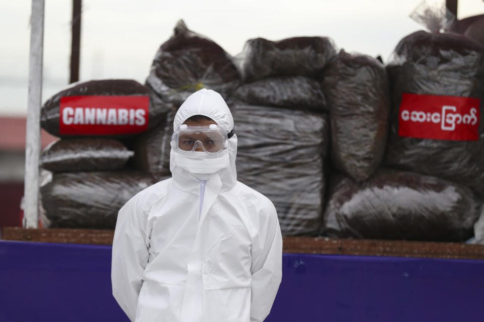 A police wearing a personal protective equipment stands in front of seized illegal drugs before being burnt during a destruction ceremony to mark International Day against Drug Abuse and Illicit Trafficking outside Yangon, Myanmar, Friday, June 26, 2020. More than $839 million of seized illegal drugs were destroyed in the country on Friday, officials said. Myanmar has long been a major source of illegal drugs for East and Southeast Asia, despite repeated efforts to crack down. (AP Photo/Thein Zaw)