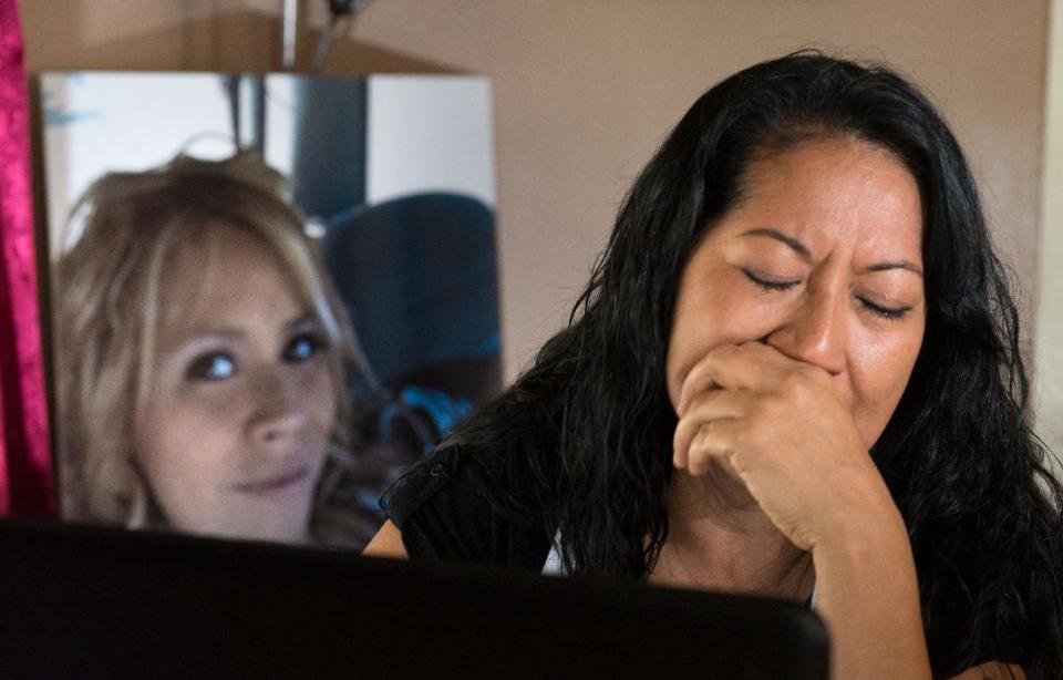 A portrait of murder victim Martha Anaya, left, is displayed on a table as her mother Herlinda Salcedo cries Sunday April 13, 2014, while looking at a computer that she used to try and find her in Santa Ana. Anaya, a sex worker, is alleged to have been slain by a pair of serial killers. Anaya's family was heavily using social media in their efforts to discover her fate. (AP Photo/Orange County Register, Eugene Garcia)