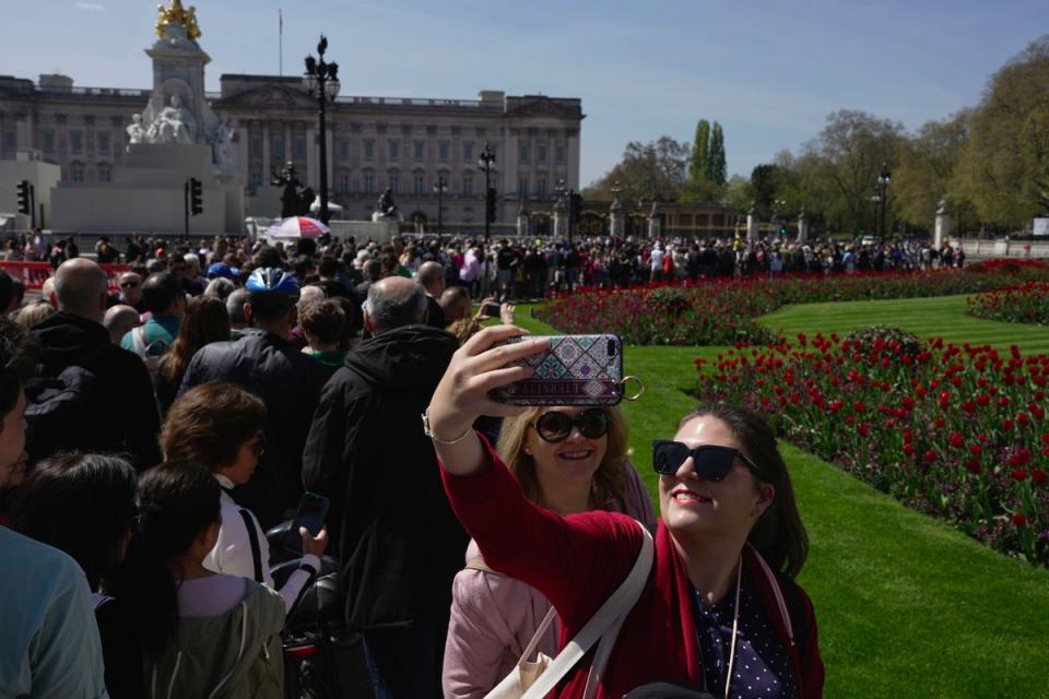 People take a selfie in front of the Buckingham Palace ahead of the coronation of Britain's King Charles III (AP)