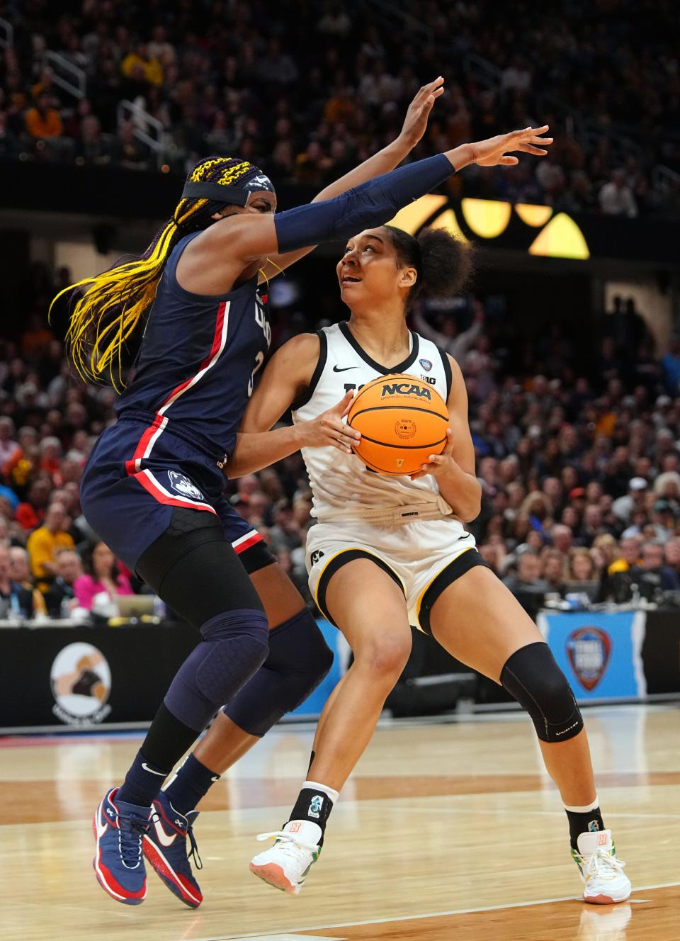 Iowa's Hannah Stuelke (45) drives to the basket as UConn's Aaliyah Edwards (3) defends during semifinals of the NCAA Women's Basketball Tournament on Friday in Cleveland.