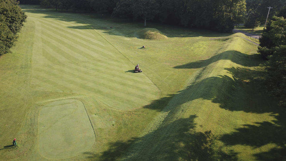 FILE - A groundskeeper mows near the flat-topped mound that is part of the 50-acre octagon at Moundbuilders Country Club at the Octagon Earthworks in Newark, Ohio, July 30, 2019. A trial was slated to begin Tuesday, May 28, 2024, to determine how much the historical society must pay for the ancient ceremonial and burial earthworks, which is among eight ancient areas in the Hopewell Earthworks system named a World Heritage Site last year. (Doral Chenoweth III/The Columbus Dispatch via AP, File)