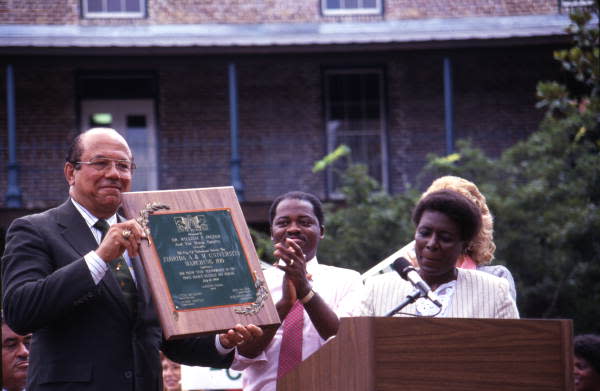 Band director William P. Foster holding an award during the celebration for FAMU's Marching 100 on Adams St. after their return from the Bastille Day Bicentennial in 1989.