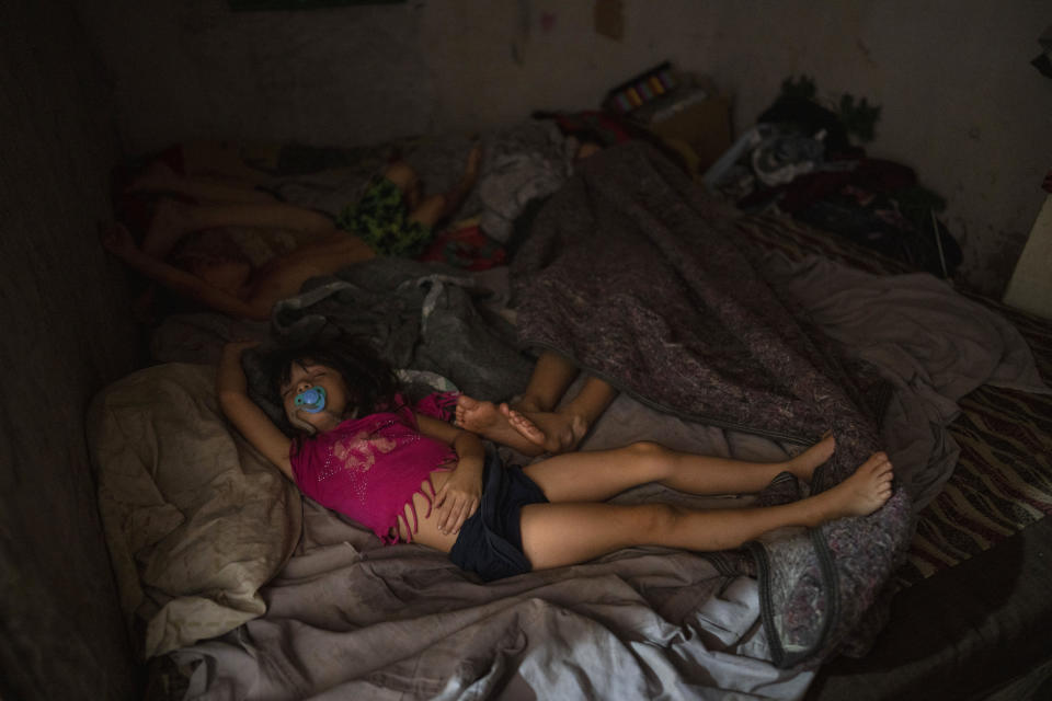 Daughters of Soledad Campos sleep inside her home where police detained her 18-year-old son as a suspect in connection with the sale of contaminated cocaine, in the Puerta 8 suburb north of Buenos Aires, Argentina, Friday, Feb. 4, 2022. A batch of cocaine has killed at least 23 people and hospitalized many more in Argentina, according to police. (AP Photo/Rodrigo Abd)